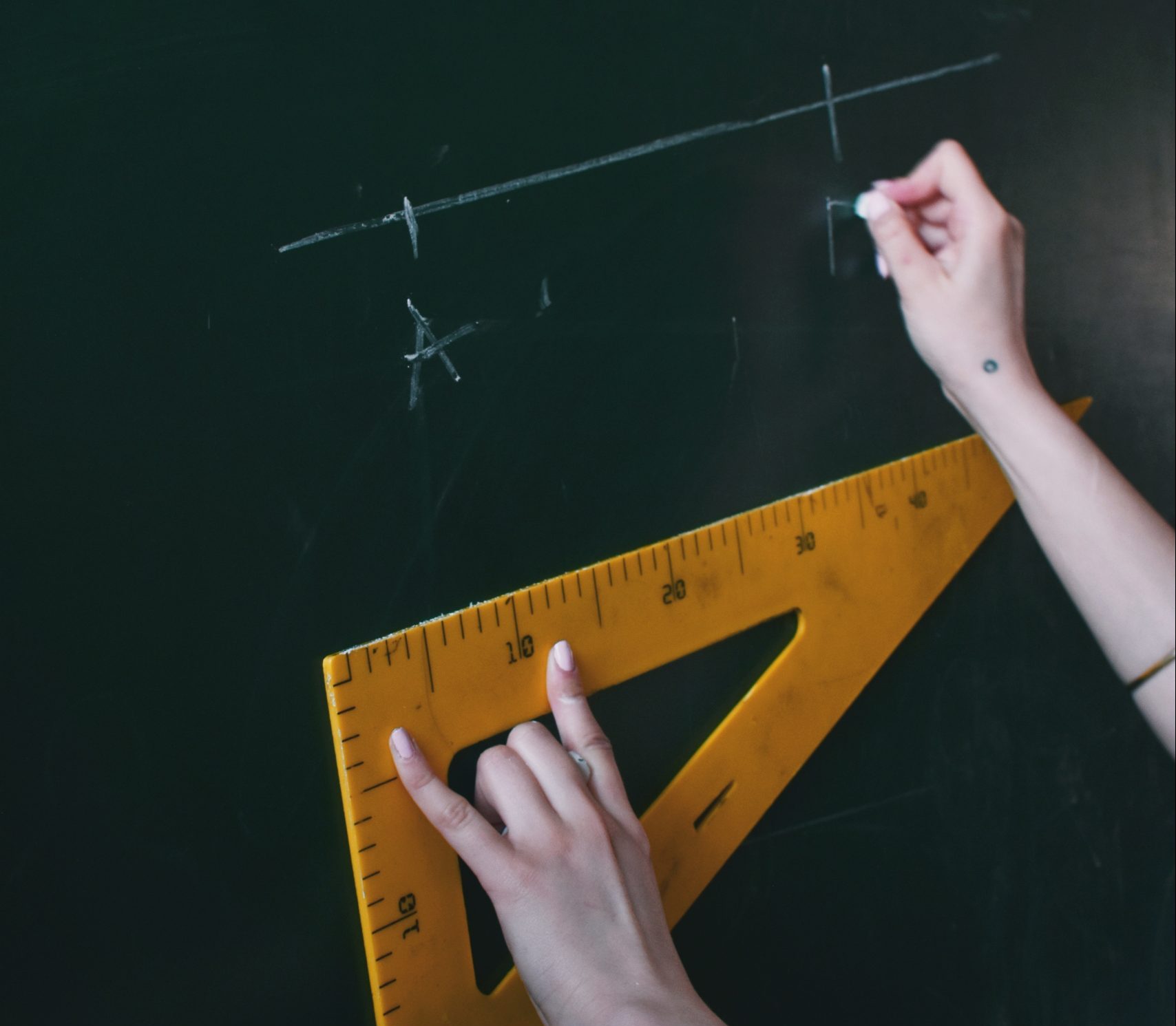 person measuring distance on a chalk board with chalk