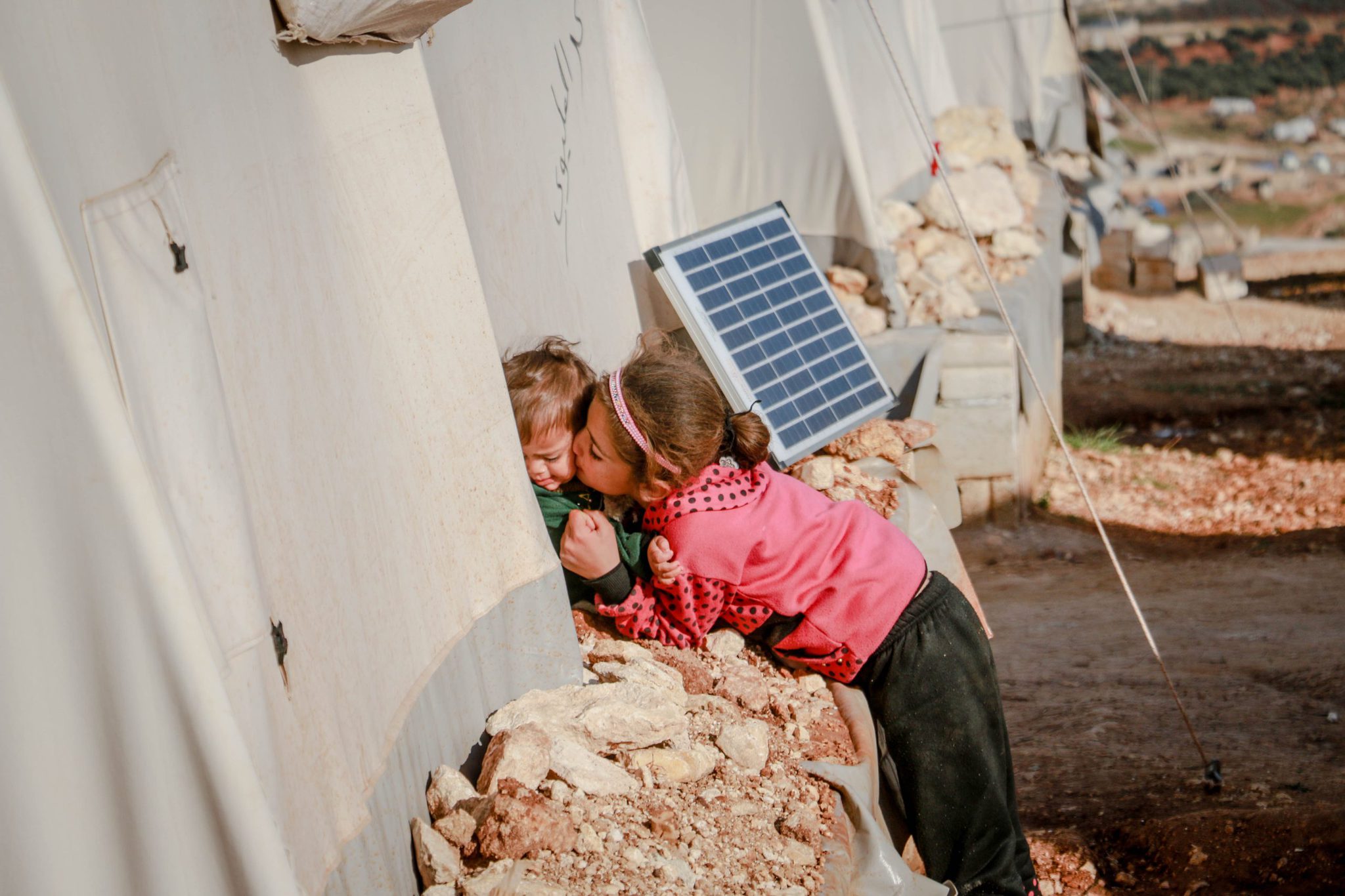a girl kissing her brother outside of a refugee camp VENTURERWRITE blog