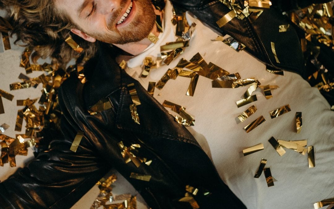 man lying on the floor with gold confetti - holiday tips Venturewrite blog