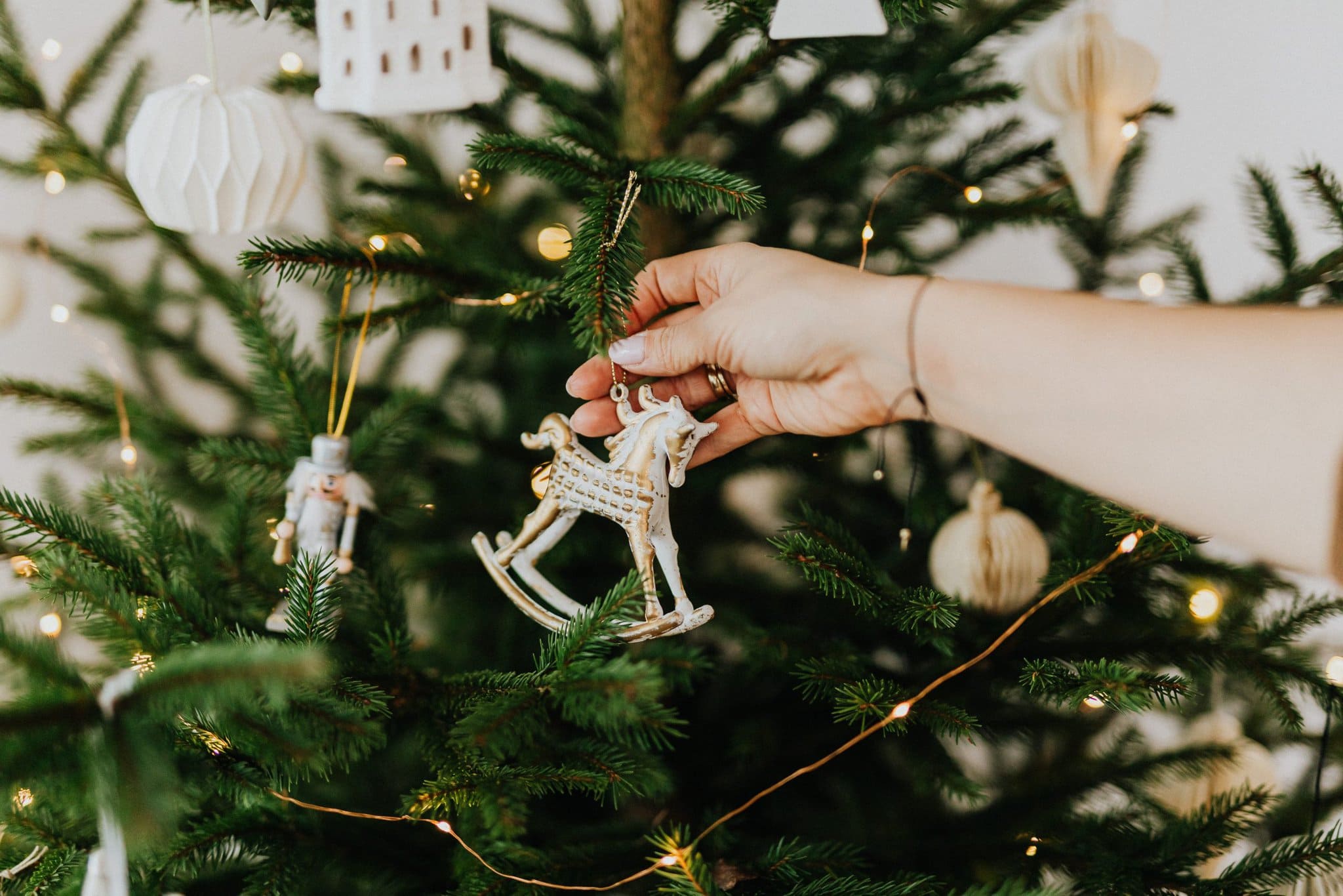 Small white rocking horse being put on a tree - for holiday tips Venturewrite blog