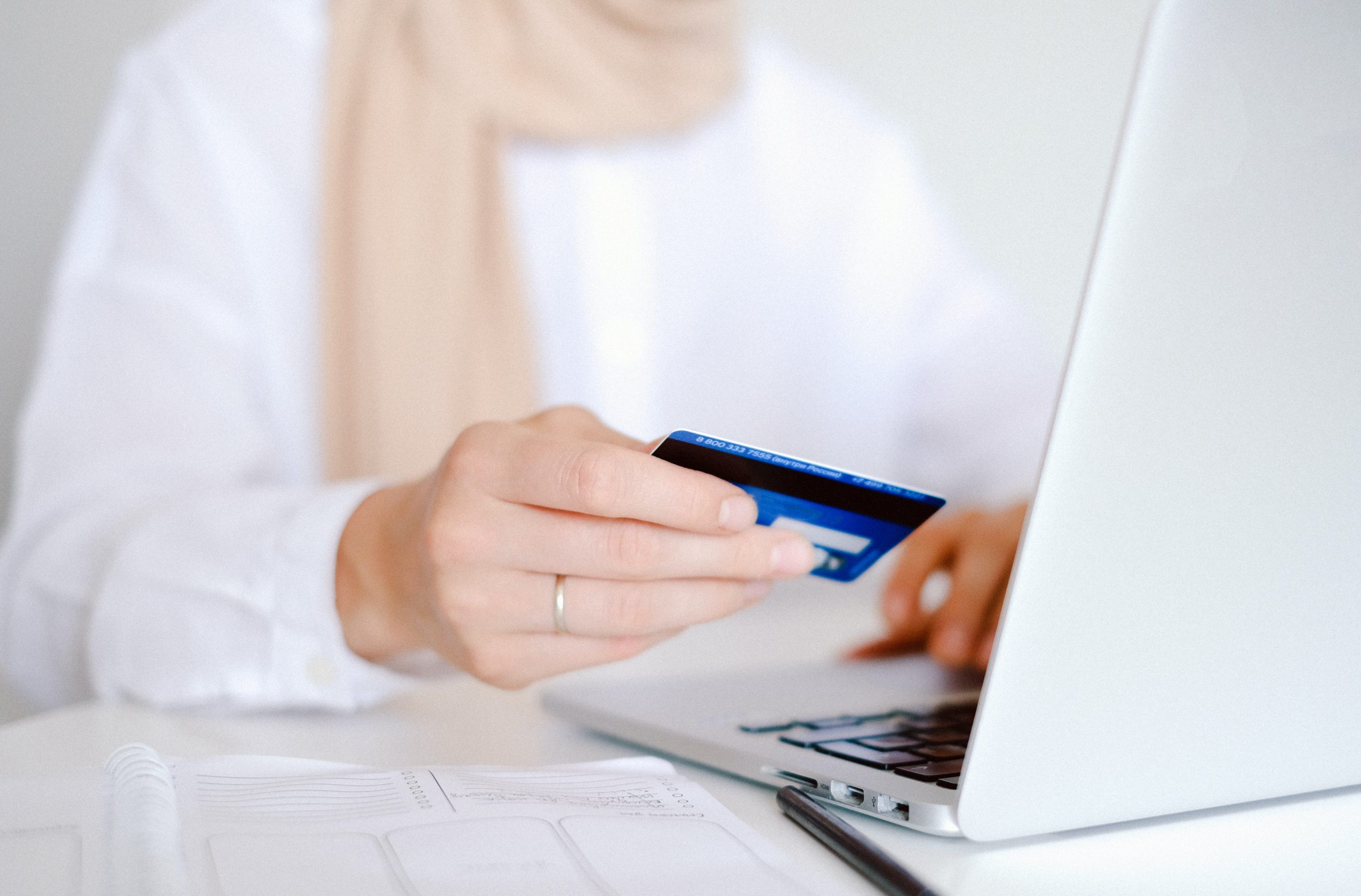 person holding a credit card in front of a laptop VENTUREWRITE marketing investment